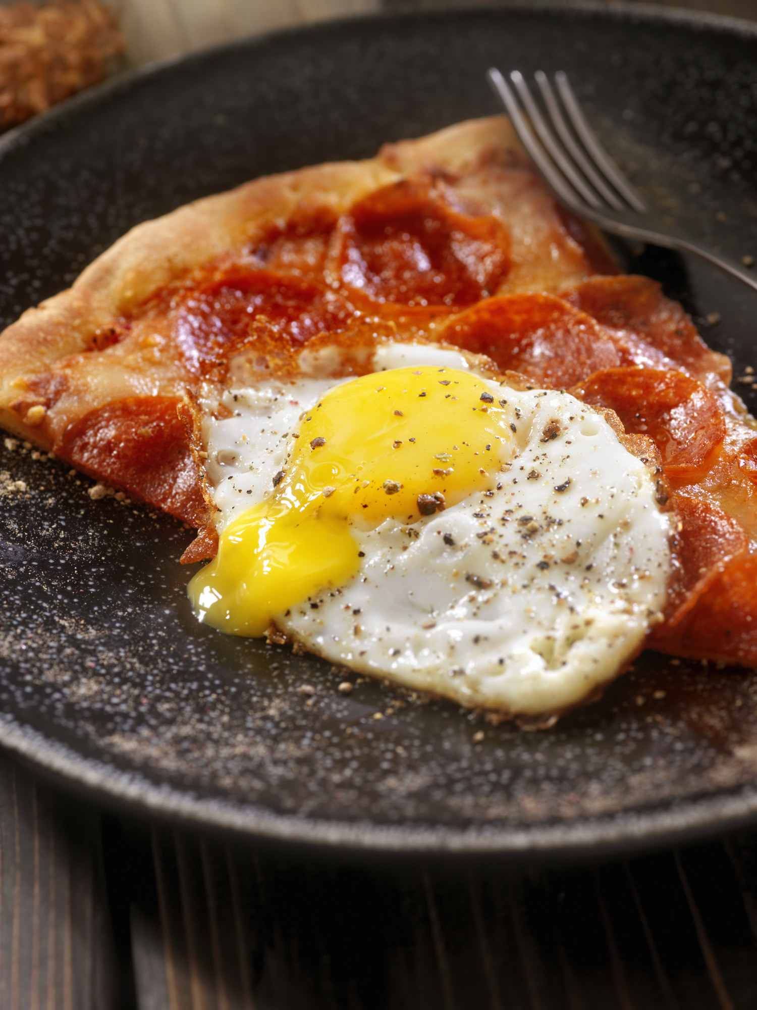 Slice of pizza with fried egg on top