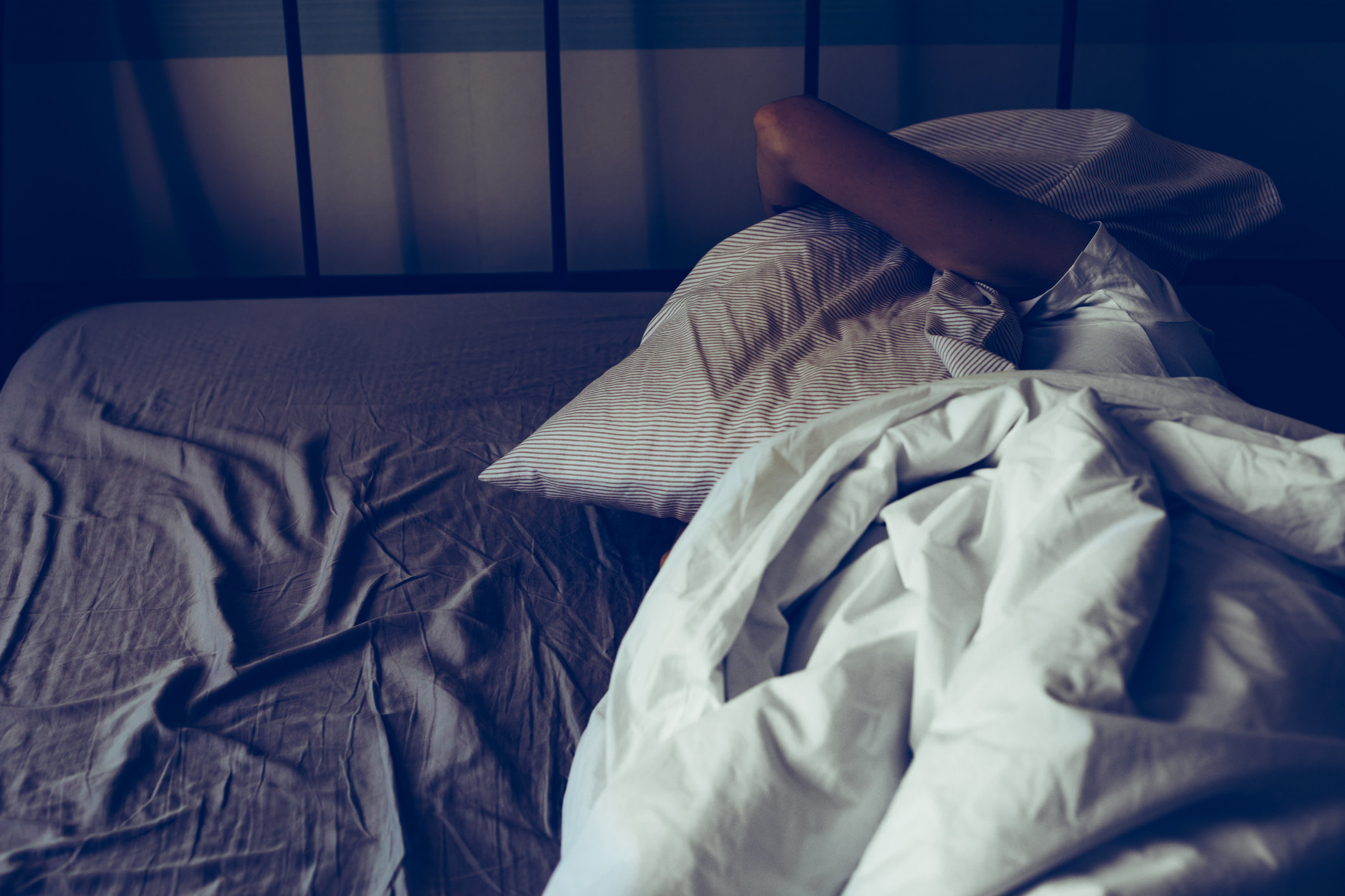 a woman covering her face with a pillow