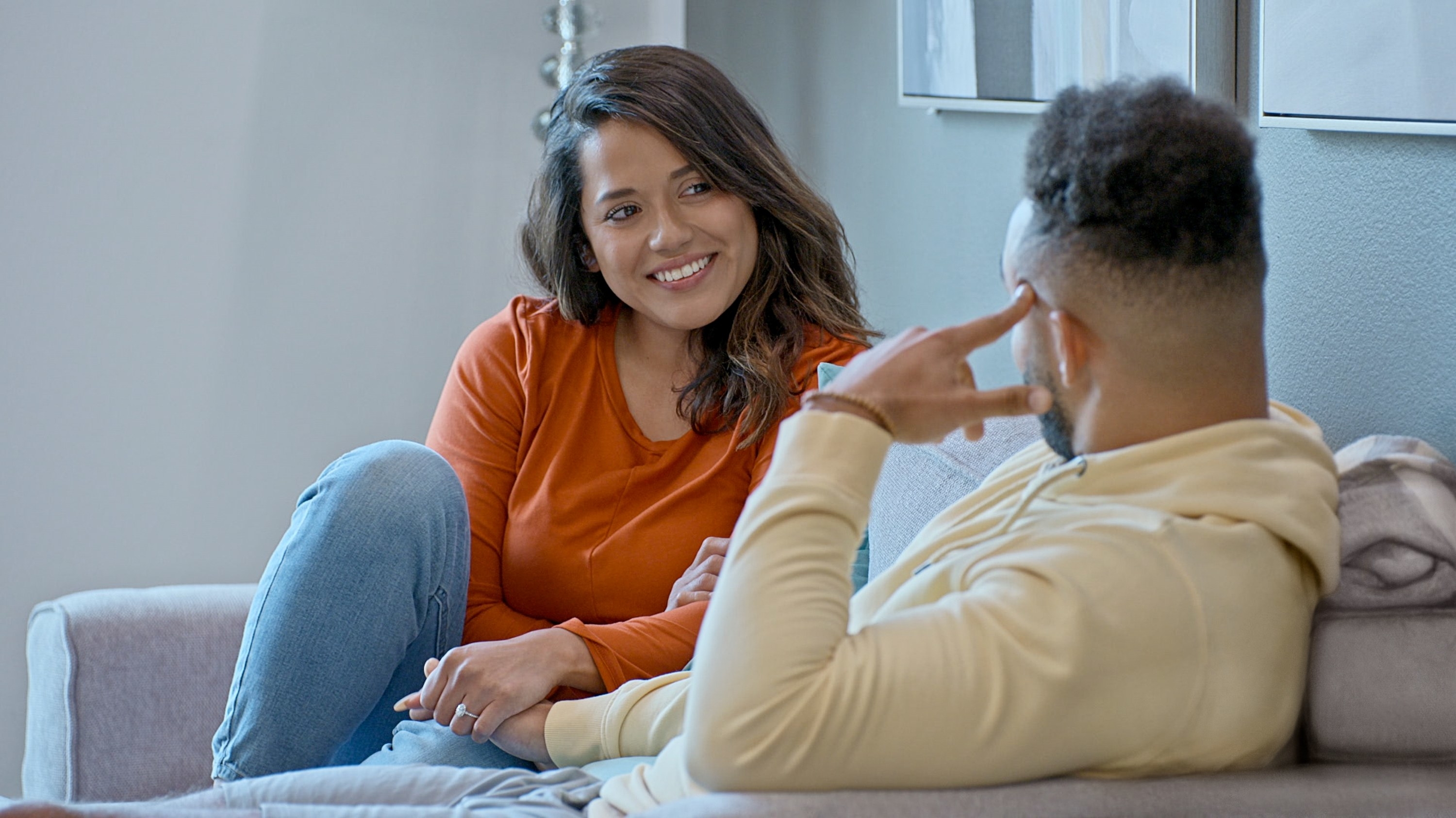 Nancy sitting on a couch with Bartise and smiling