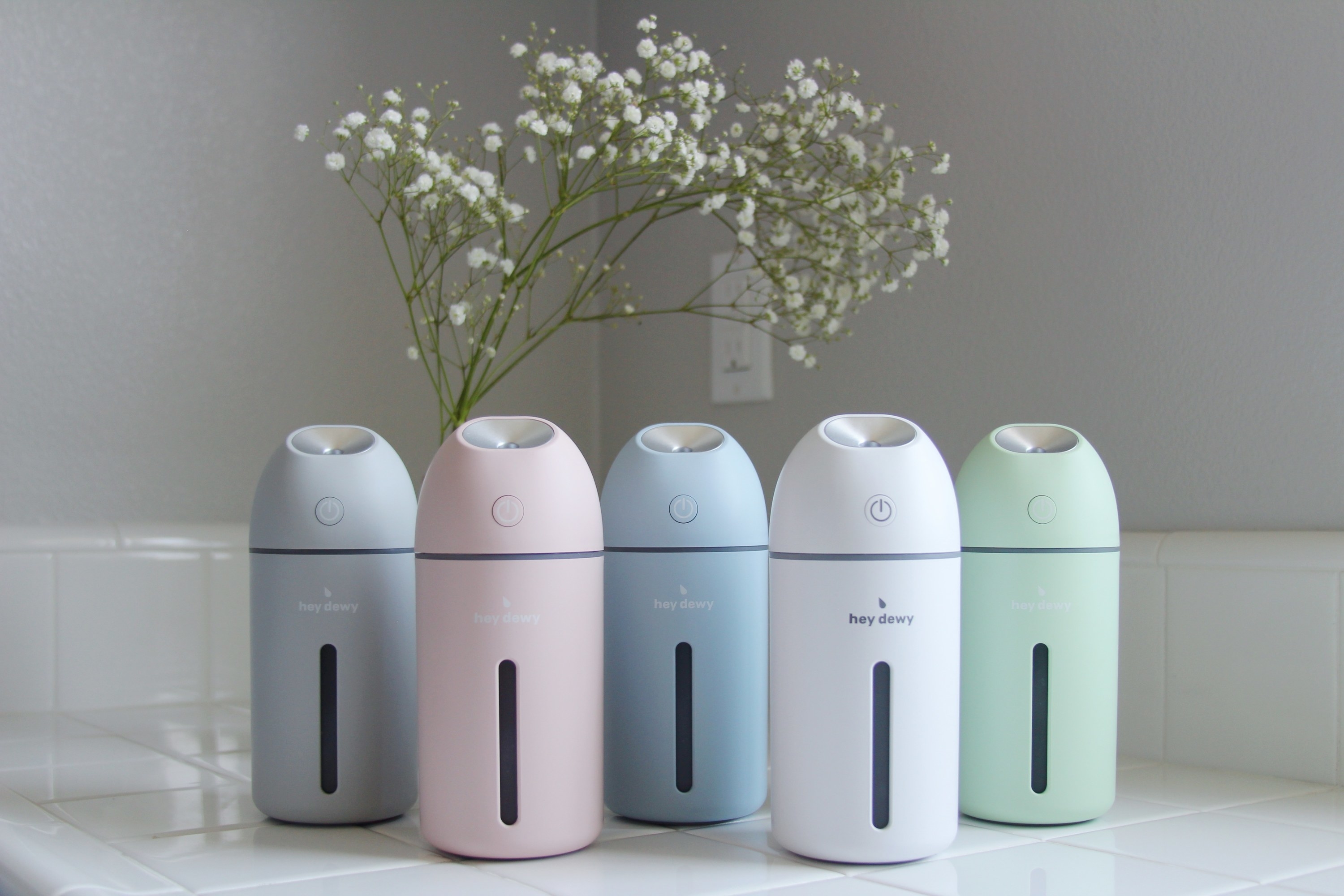 Hey Dewy humidifiers in different colors on white counter.