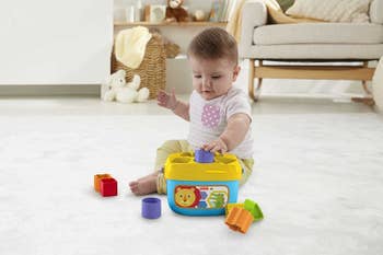 A baby playing with the shape sorting bucket