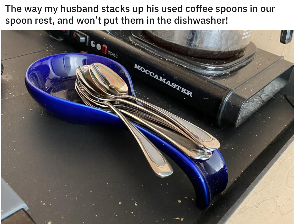 A large stack of spoons sits on a counter, with text saying the picture taker&#x27;s husband refuses to put them in the dishwasher