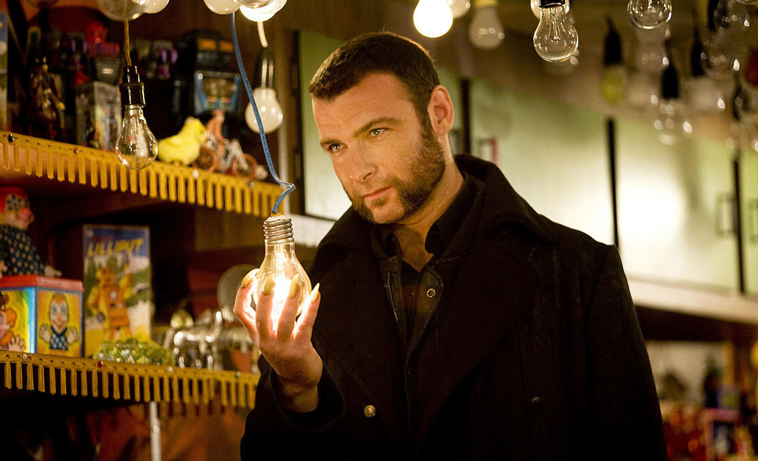 A man with mutton chops, an overcoat and sharp fingernails holds a light bulb menacingly
