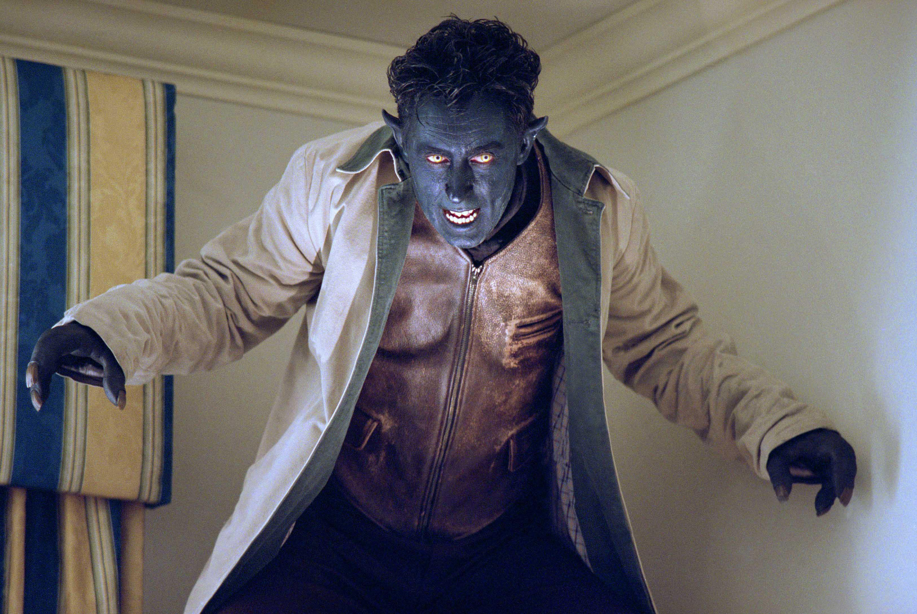 A blue skinned, demonic looking mutant in an overcoat stands in the corner of a room