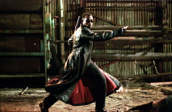 A vampire hunter in a long leather coat tosses a throwing star at a villain in an abandoned warehouse