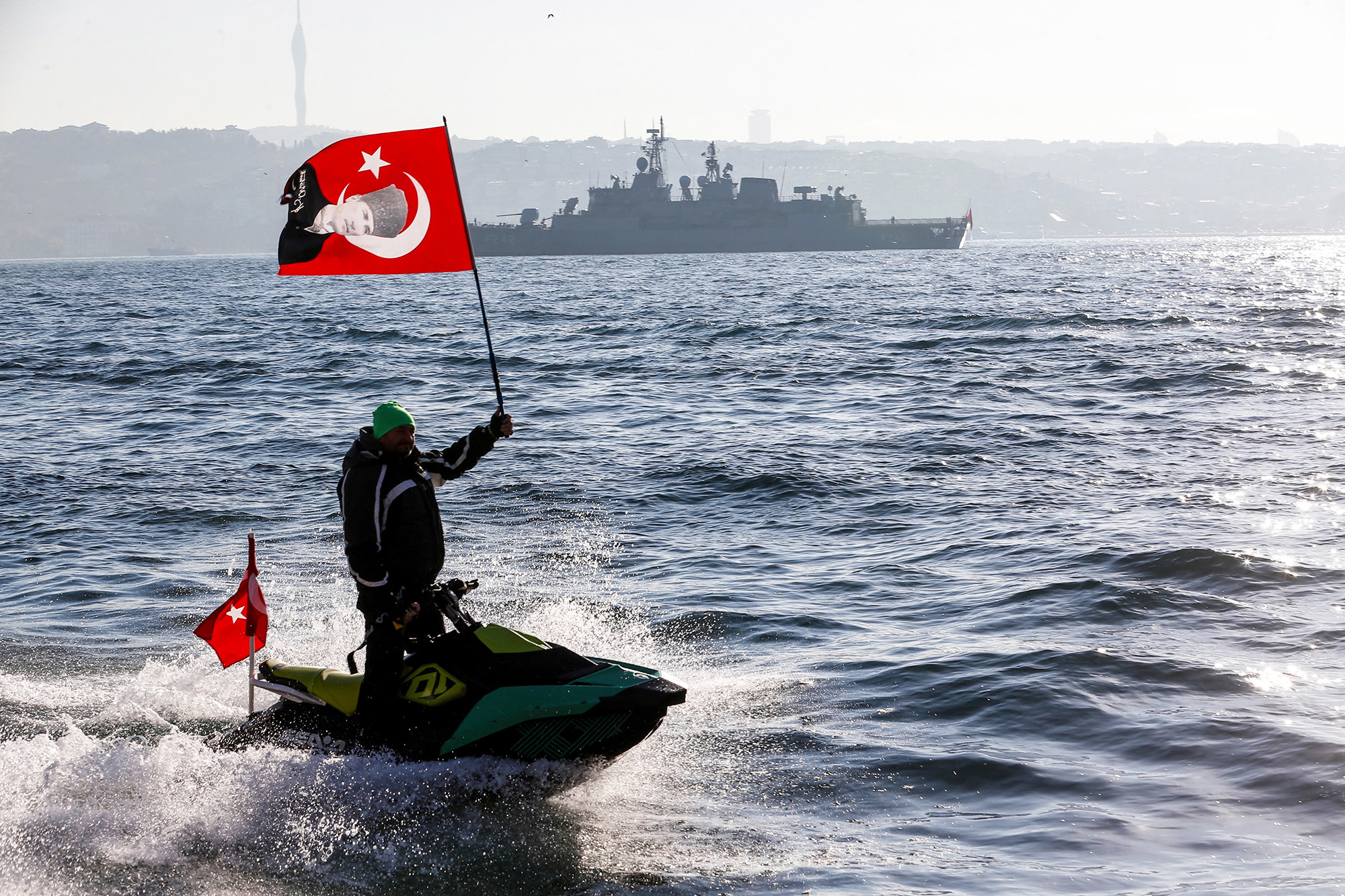 someone on a jetski holding a turkish flag as they sail in open water