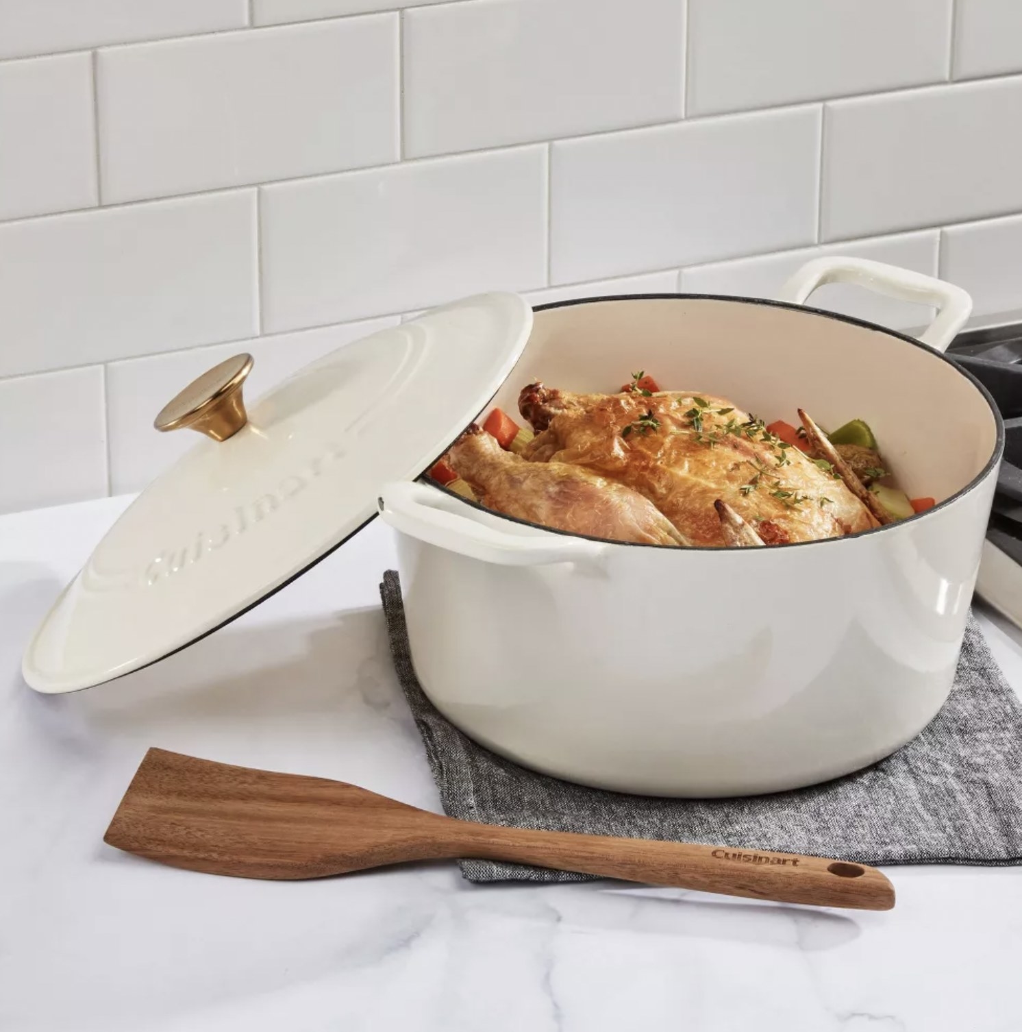 The white casserole dish with roast chicken and veggies resting on counter