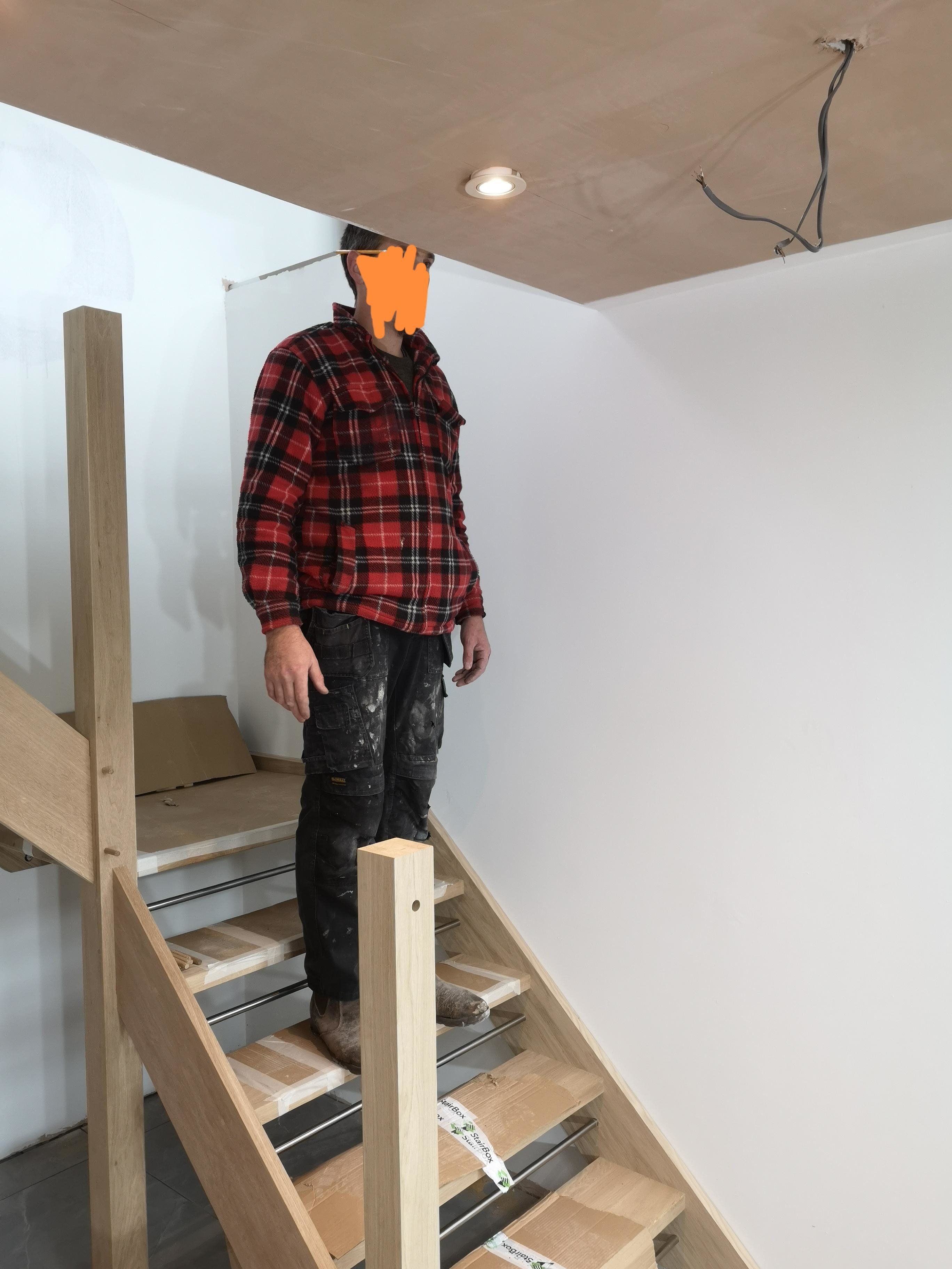 Person standing on a step with their head extending above the ceiling