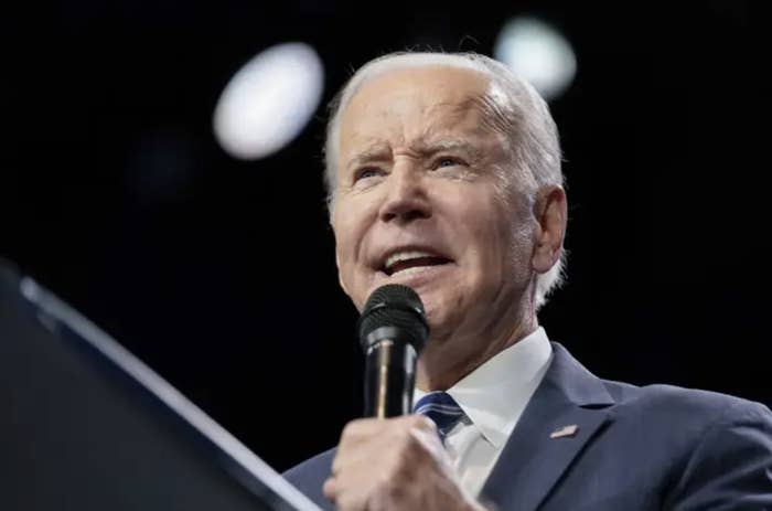 zoomed in shot of joe biden holding a microphone in a suit