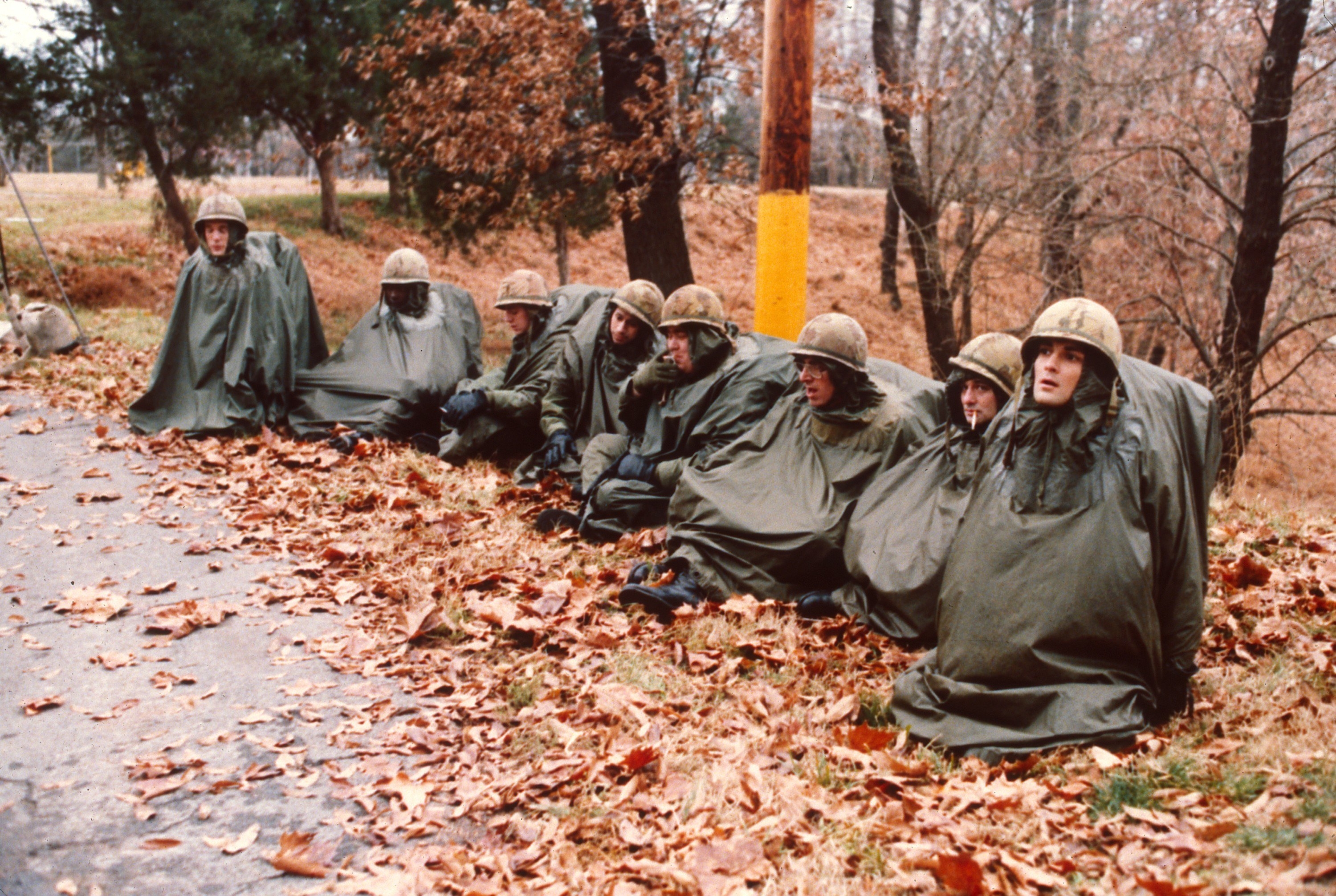 People wearing helmets and sitting in a row wearing tarpaulin-type capes