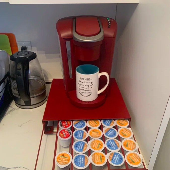 Reviewer image of red coffee maker with coffee pods under it