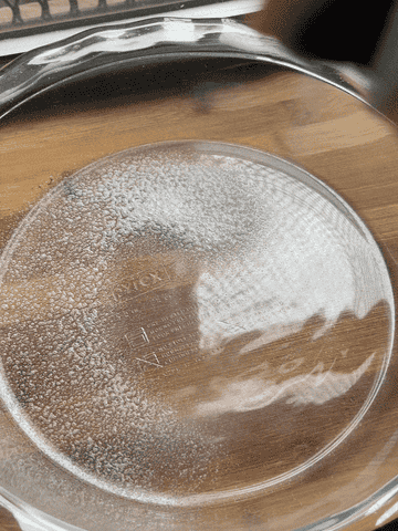 spraying cooking spray all over a glass pie dish