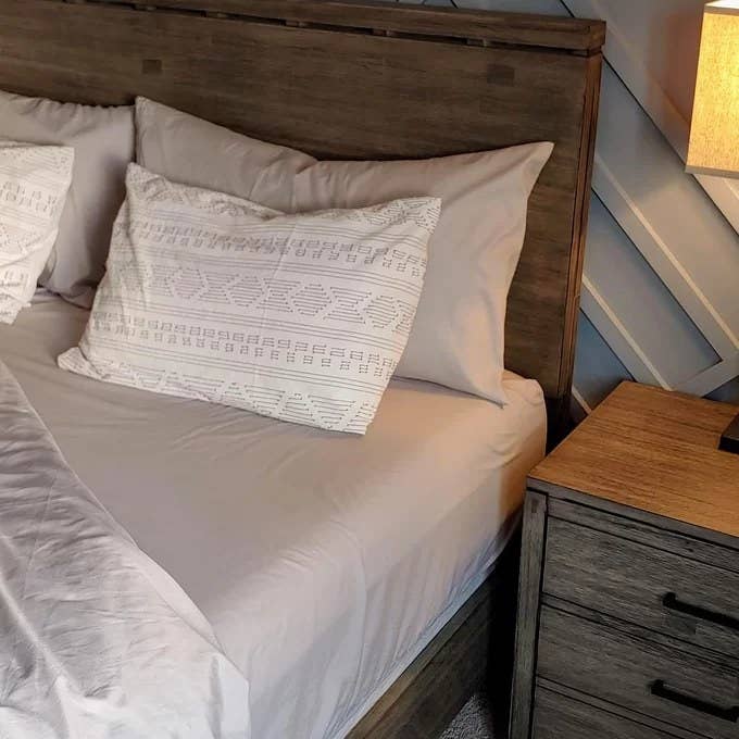 Reviewer image of gray sheets on a wood bed