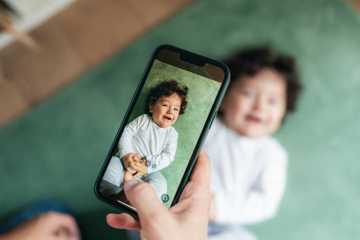 a hand taking a photo of a baby