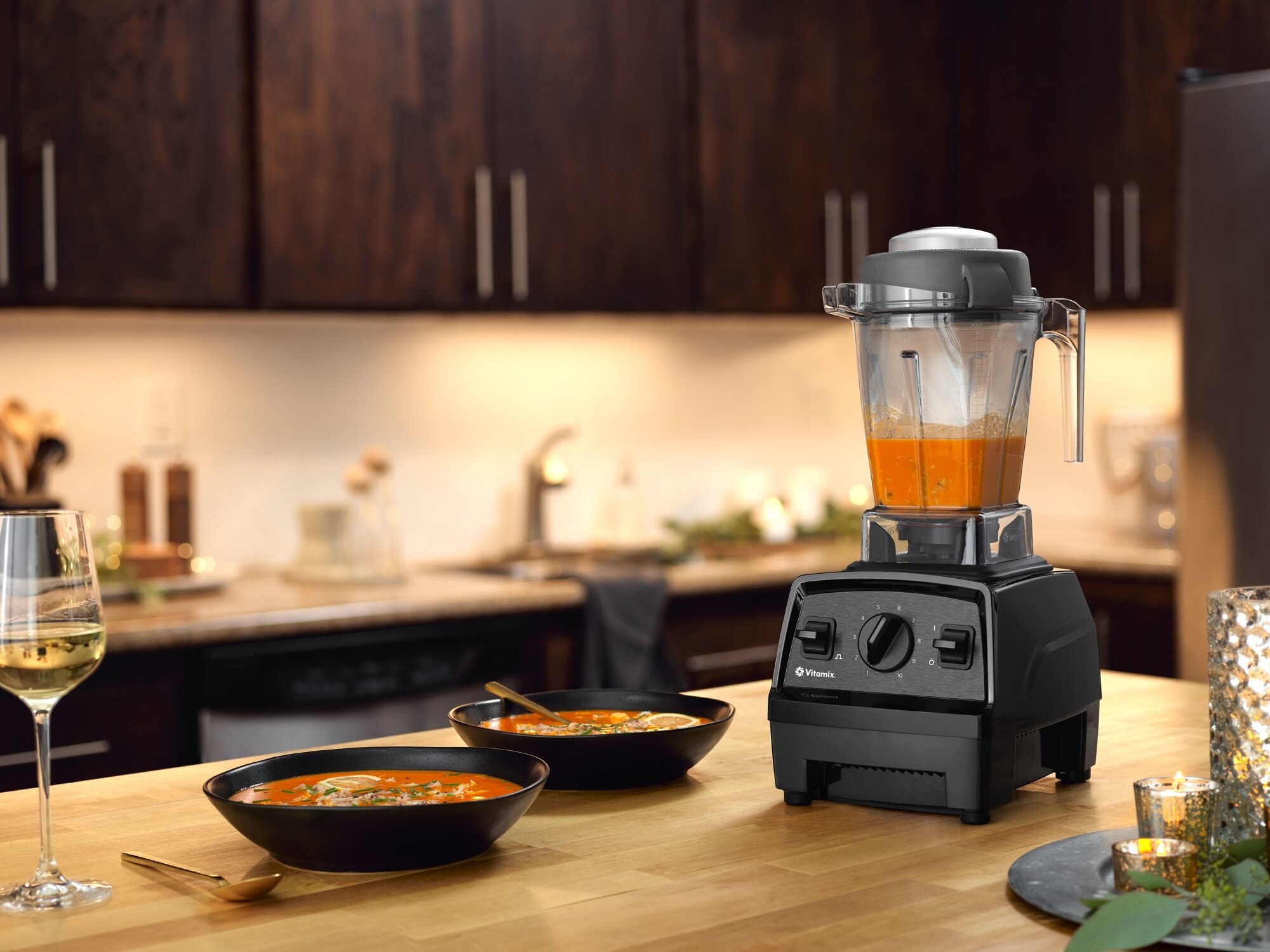 Vitamix blender with soup next to two bowls