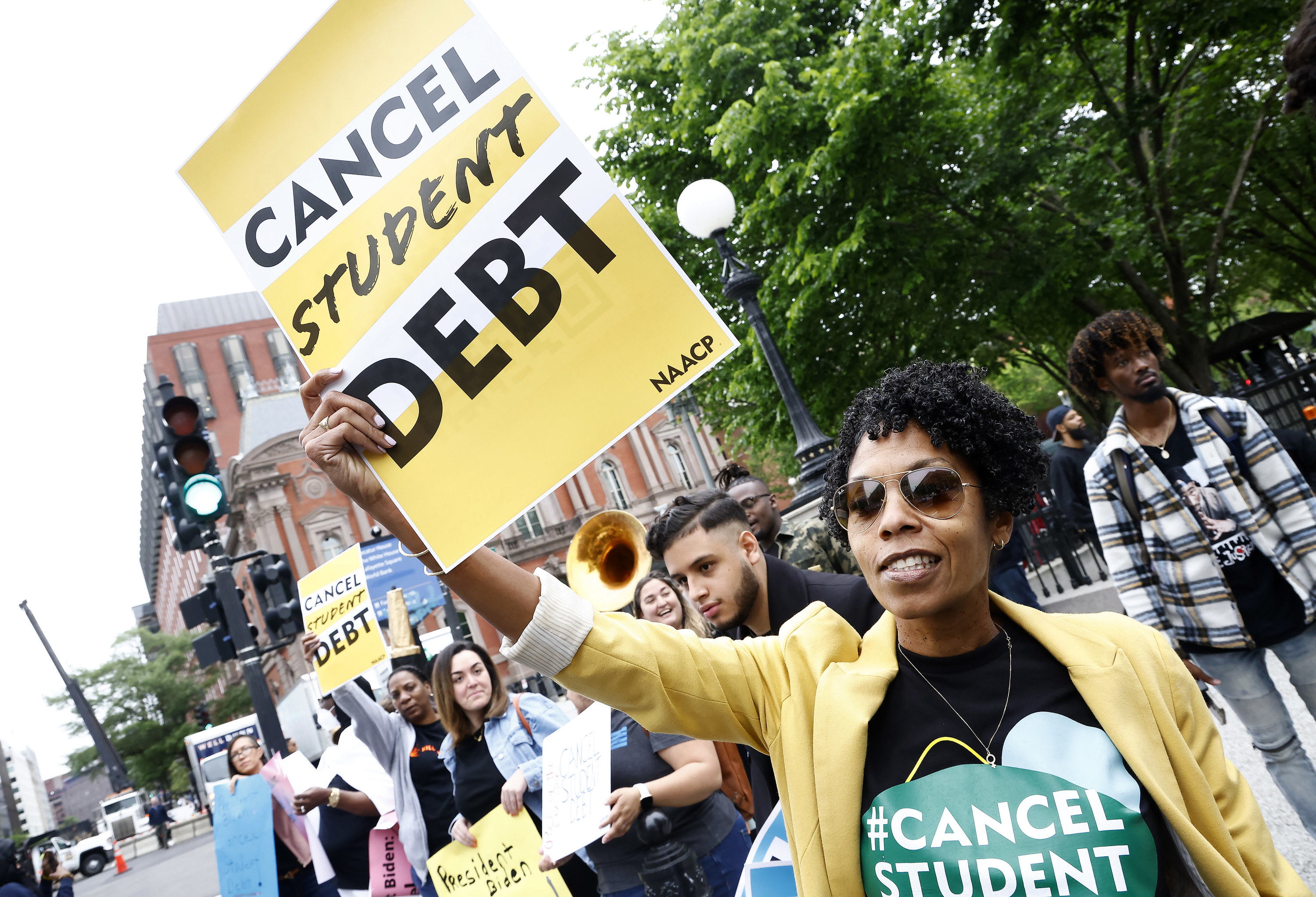 A demonstrator among others holds a sign reading cancel student debt