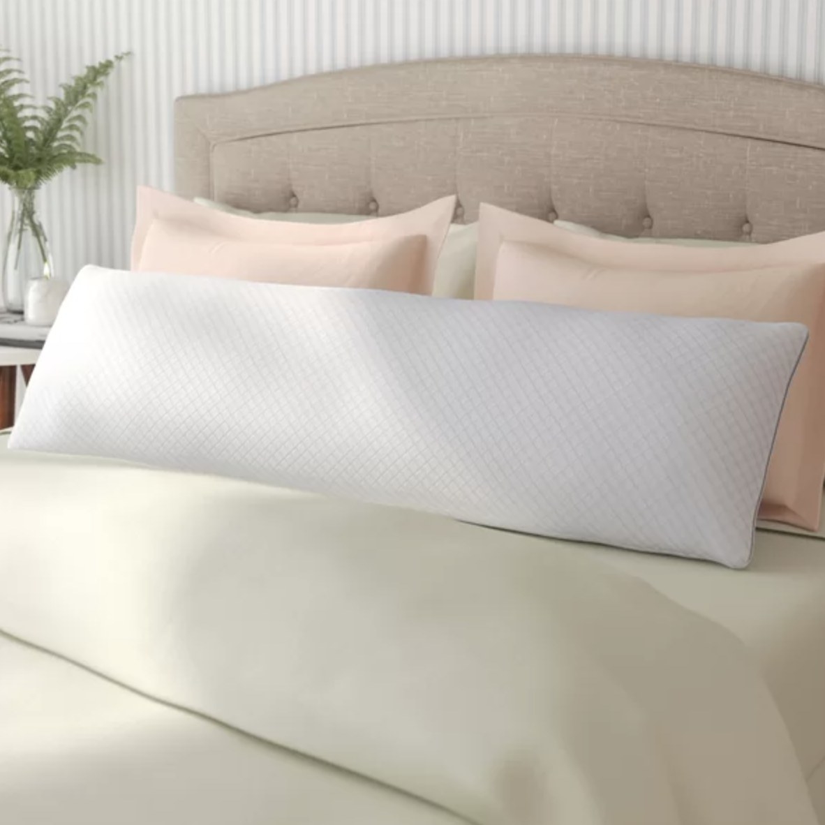 The white, cool body pillow is against a neutral bed
