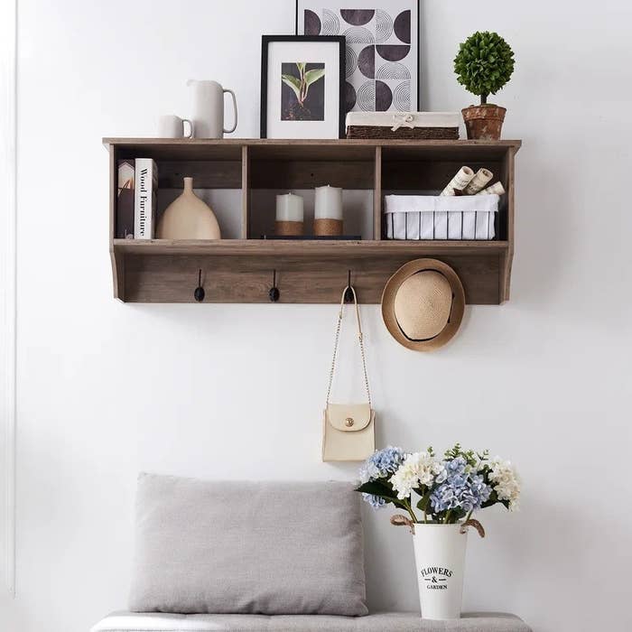 The mounted wall rack with a hat and purse hanging from the hooks, and decor items in the storage space.