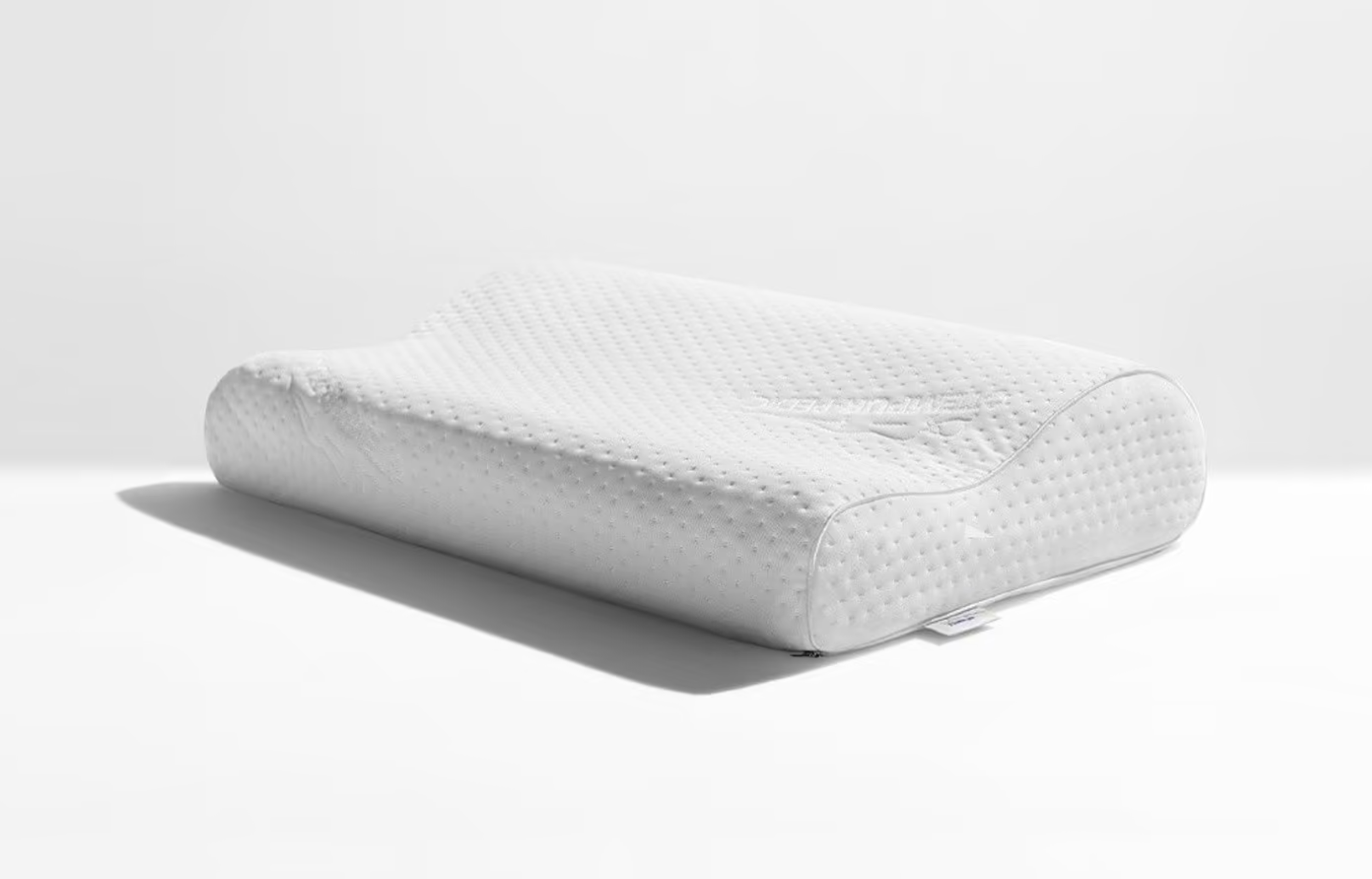 A white pillow. One horizontal half of the pillow is thicker than the other half.