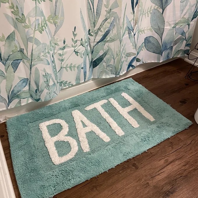 Reviewer image of teal  bath mat next to a tub