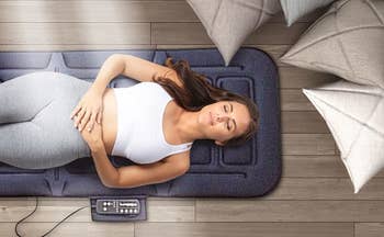 model lying down flat on floor on top of the massager