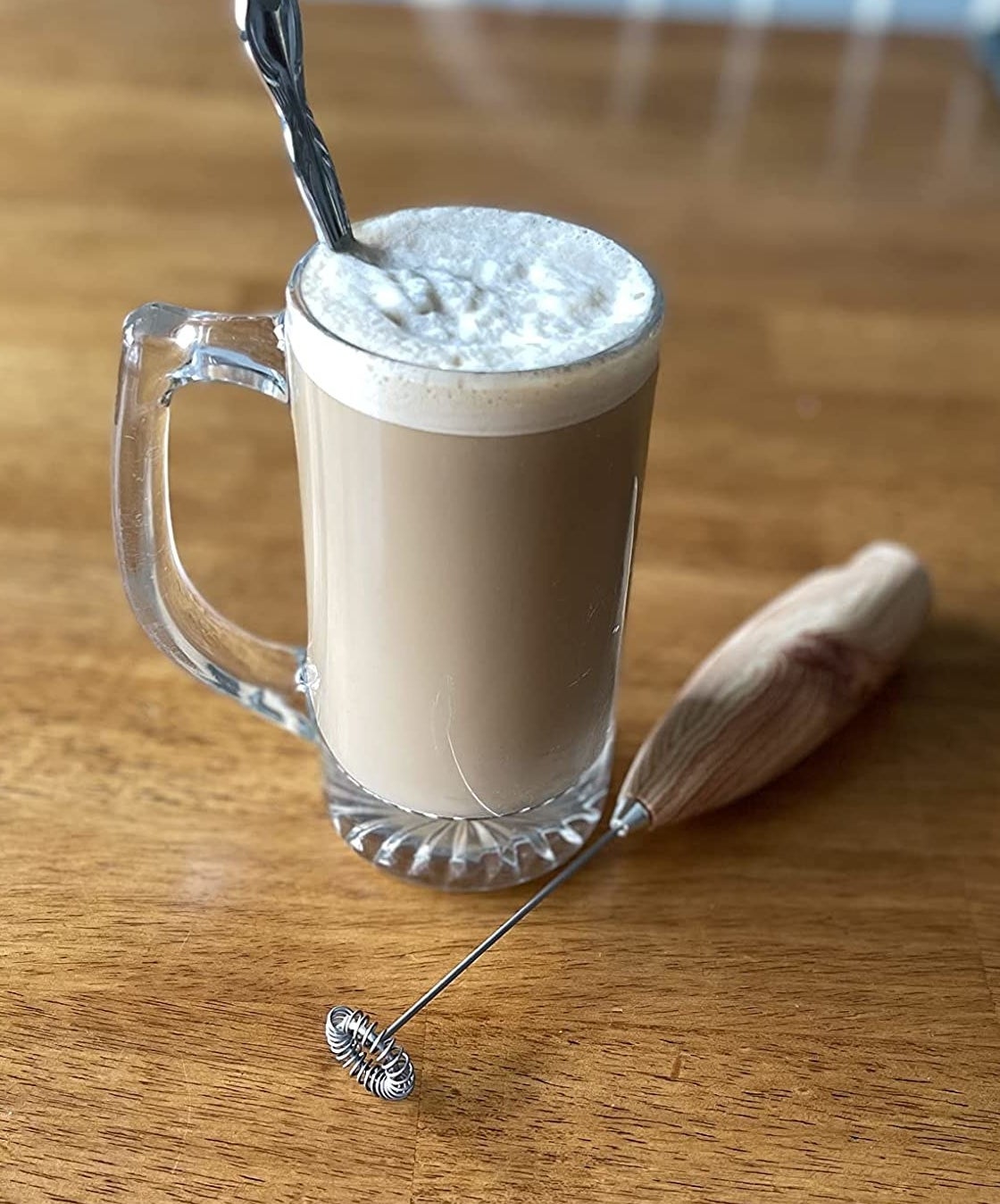reviewer photo of the frother and coffee in clear glass topped with foam milk