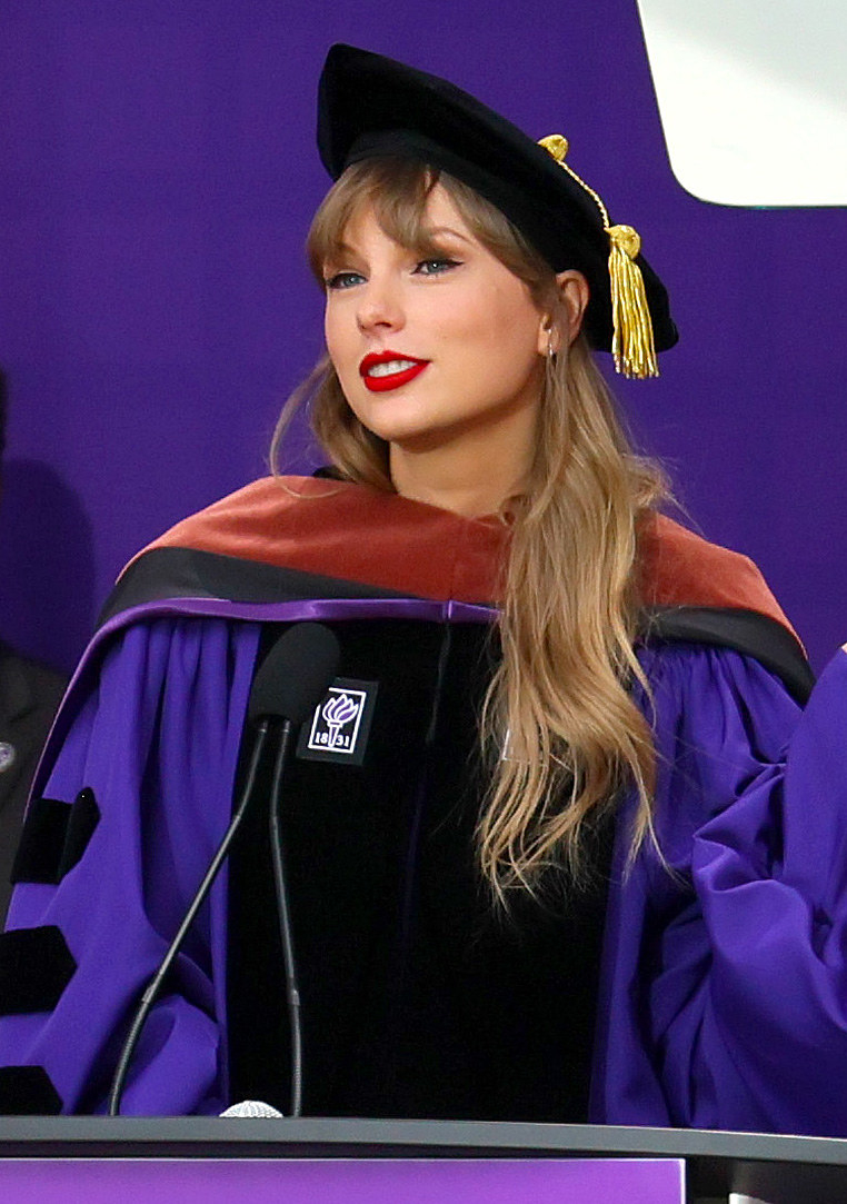 Taylor in a graduation cap and gown speaking at a podium