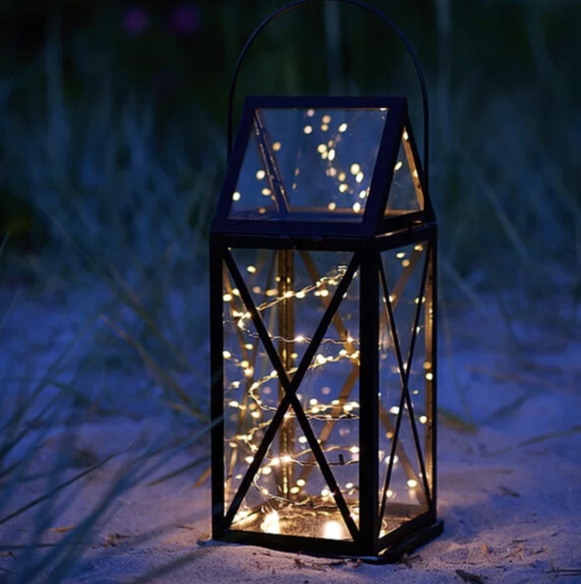 The lit fairy lights are inside a black and clear panel lantern outside