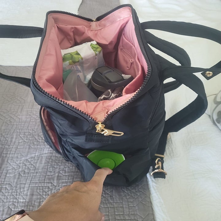 reviewer photo inside of black anti-theft backpack with pink lining