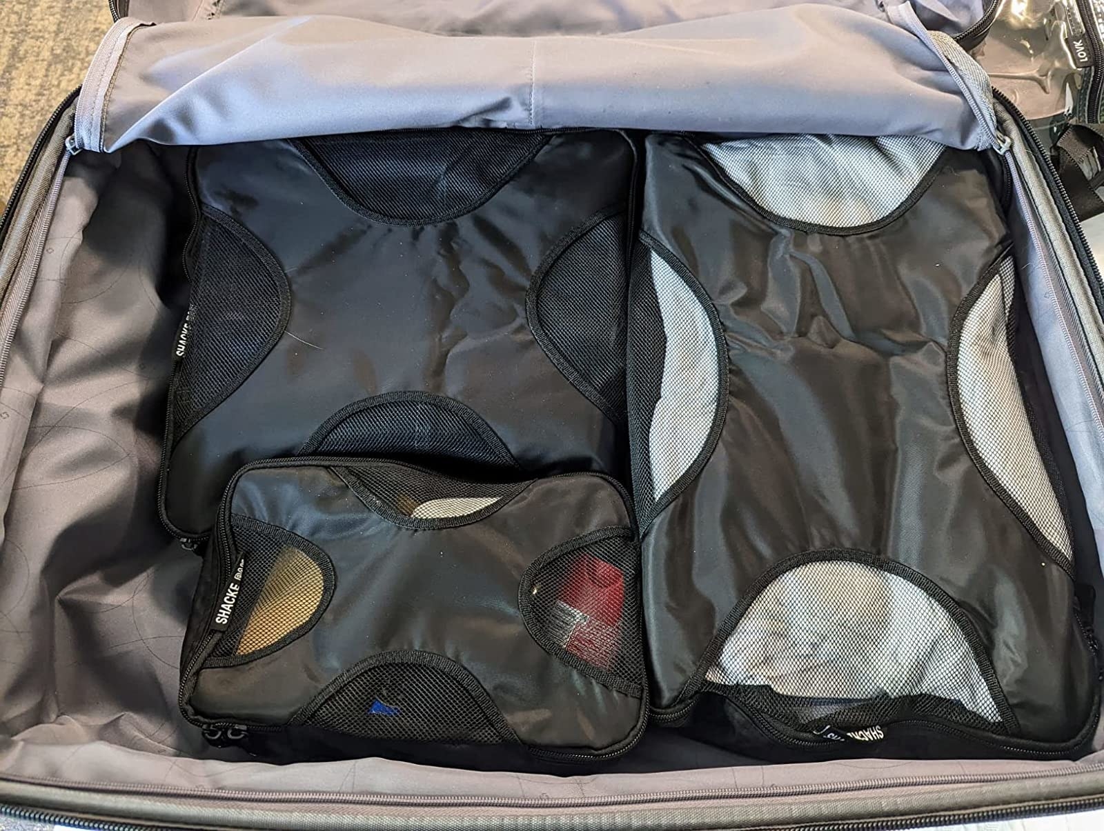reviewer photo of three gray packing cubes inside a suitcase