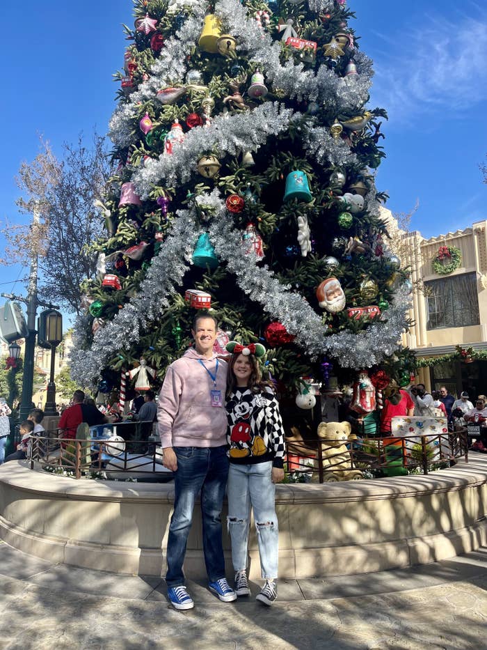 the author and his daughter smiling by a Christmas tree at Disneyland
