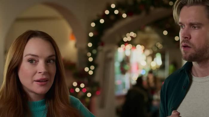 Lindsay Lohan stands next to Chord Overstreet with Christmas decorations in the background