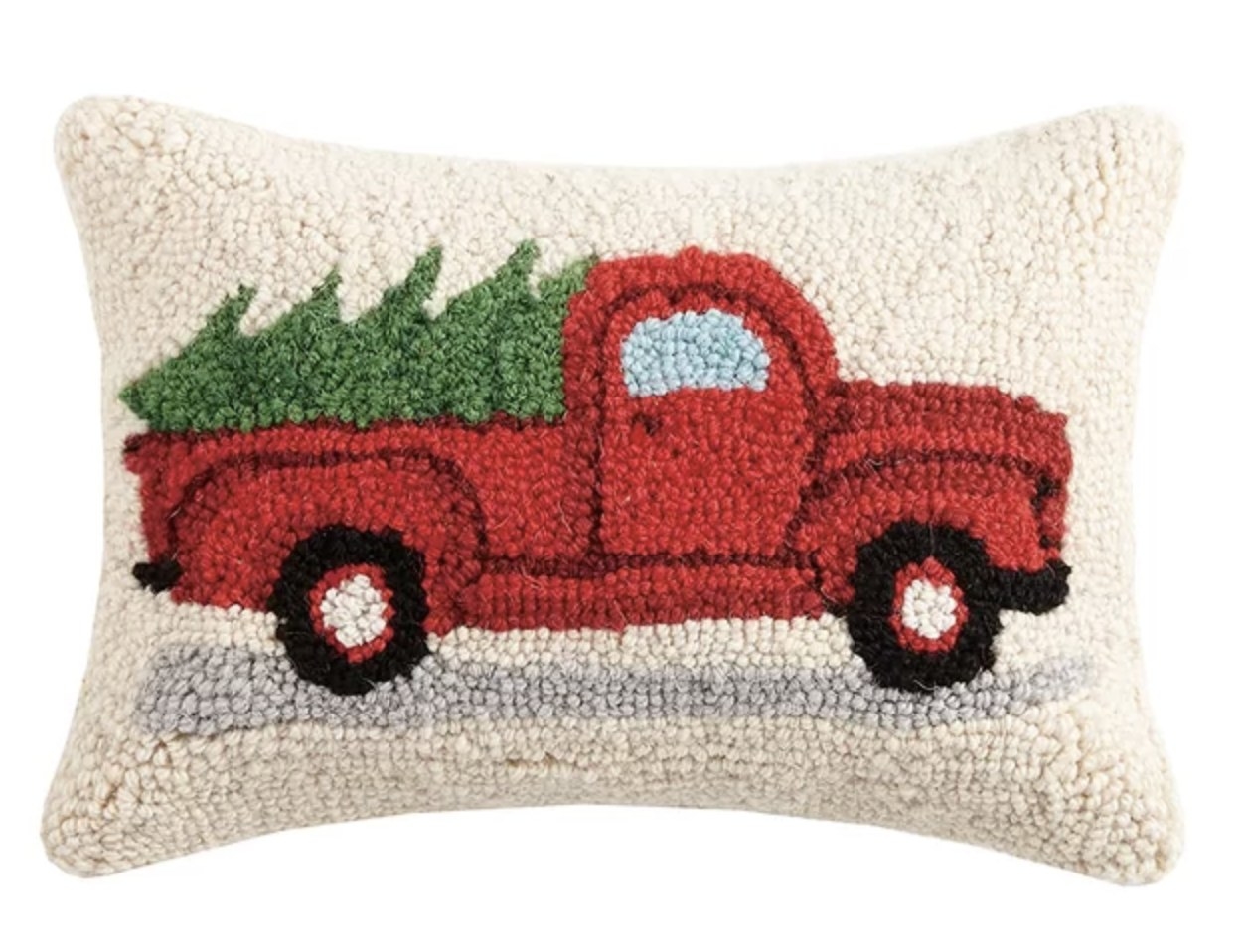 The white pillow has a red truck lugging a green tree in the trunk