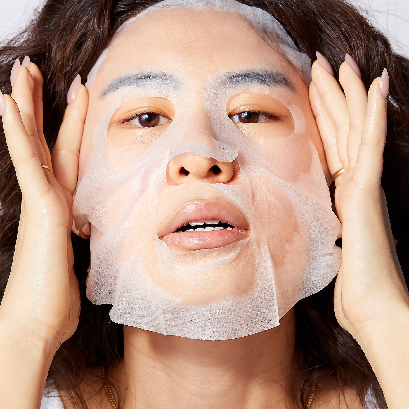 model putting on a white sheet face mask