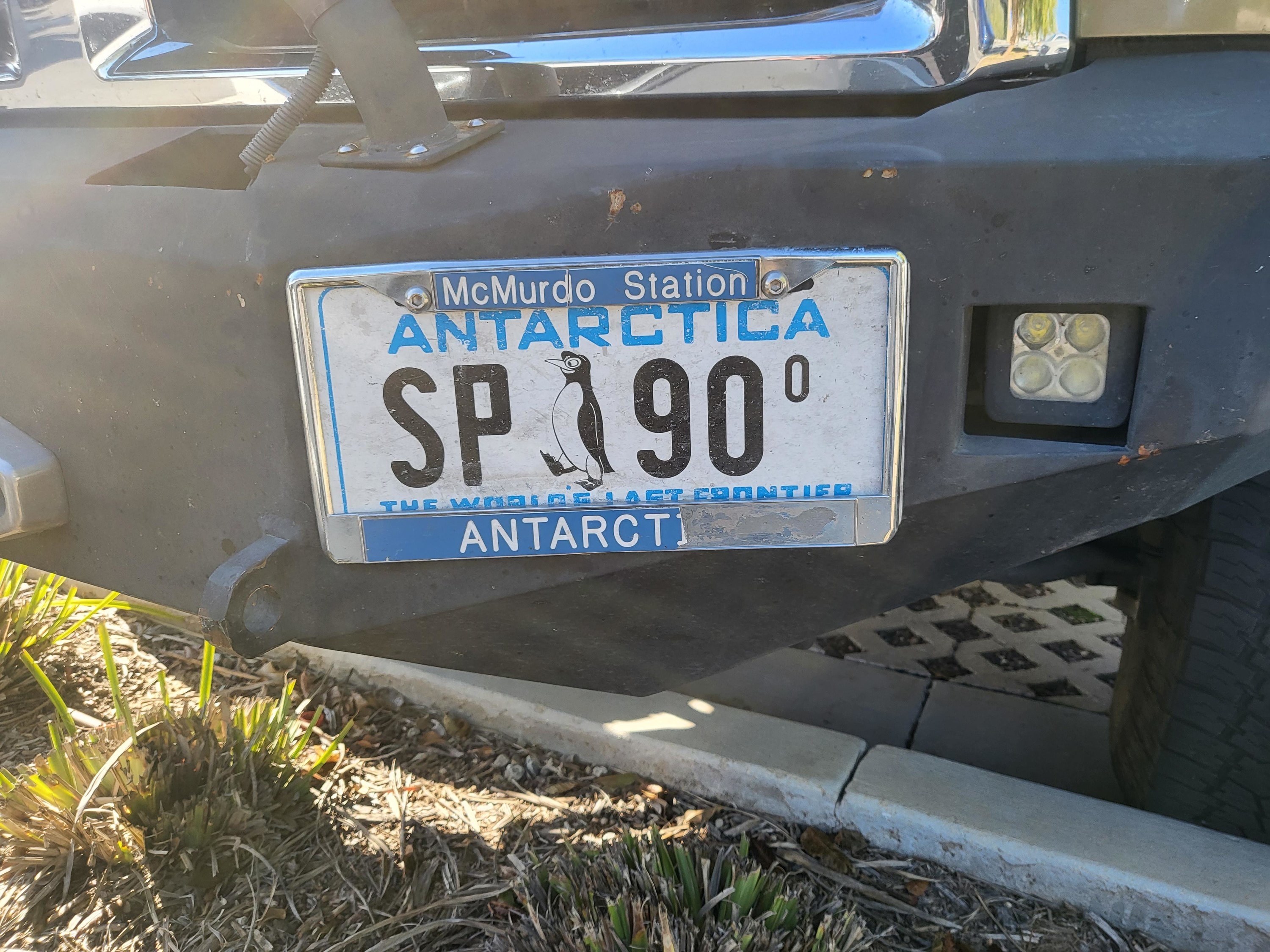 Antarctica license plate, with two letters and two numerals and a penguin in the middle of the plate and &quot;The world&#x27;s last frontier&quot; slogan