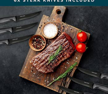 cooked steak on a wooden cutting board surrounded by six steak knives