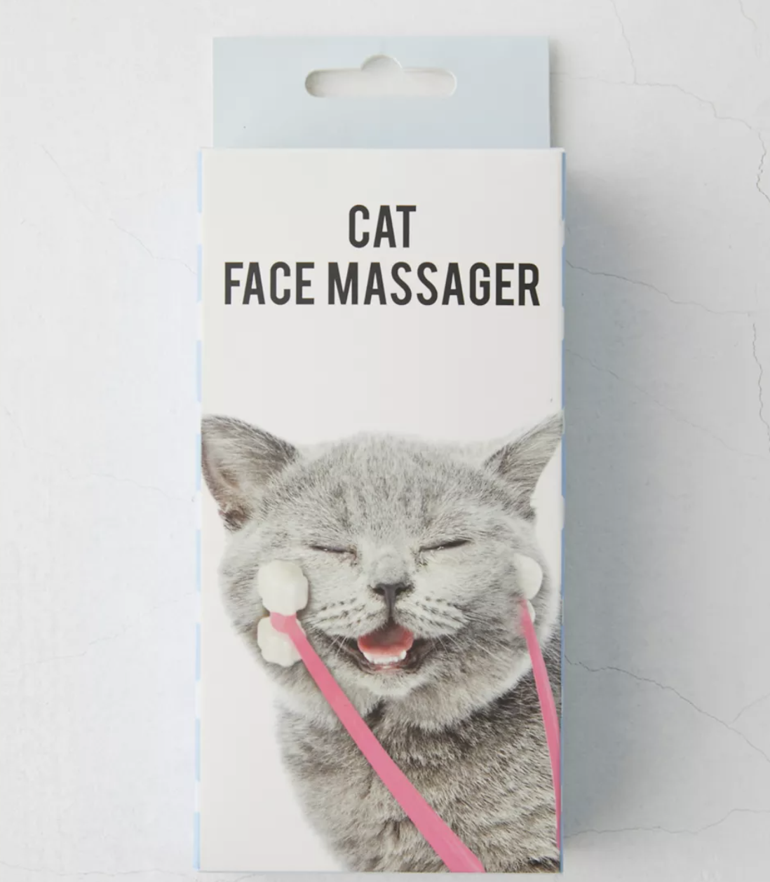 the box with a photo on it showing a cat&#x27;s face being massaged in front of a plain background