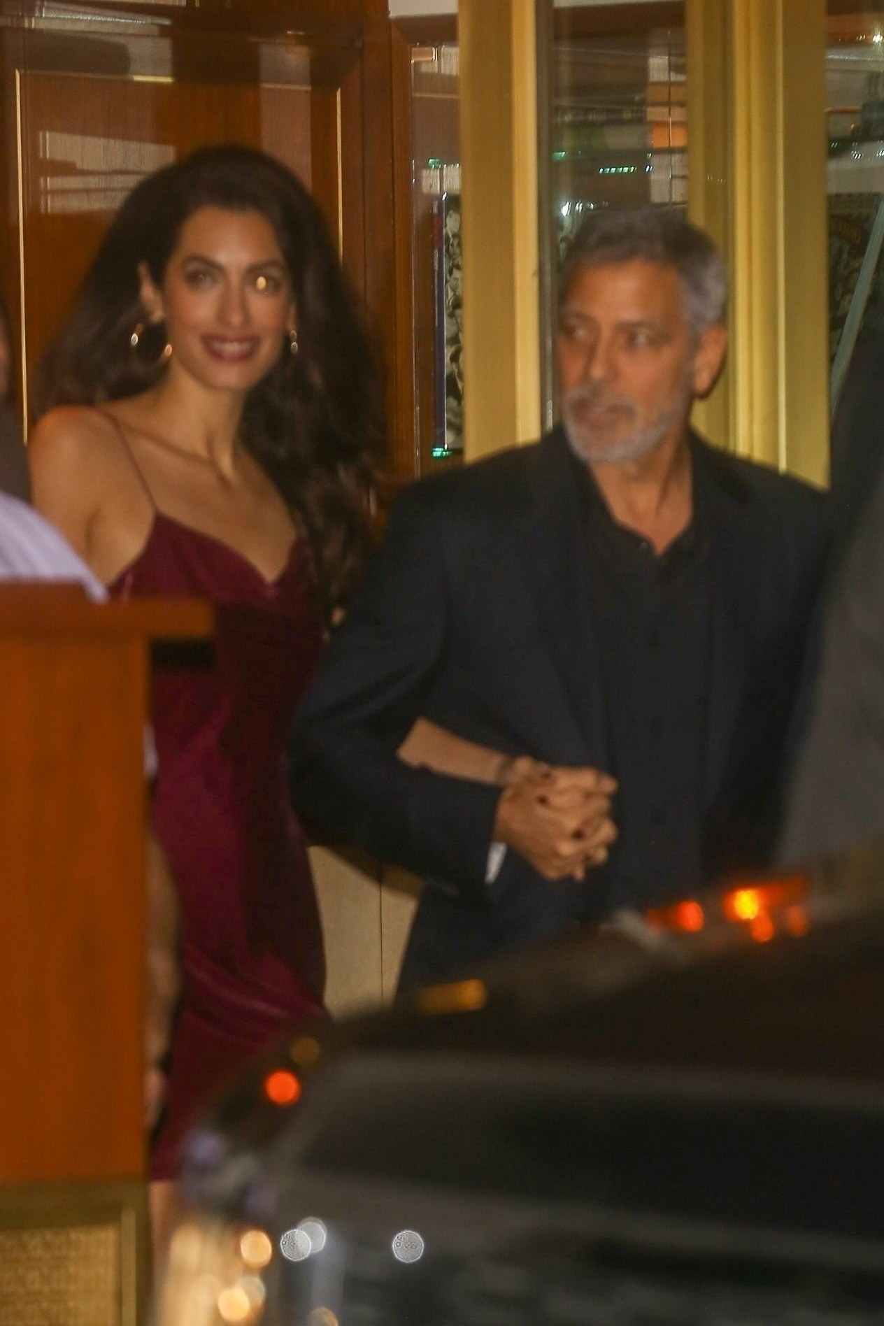 The couple holding hands as they walk out of a building