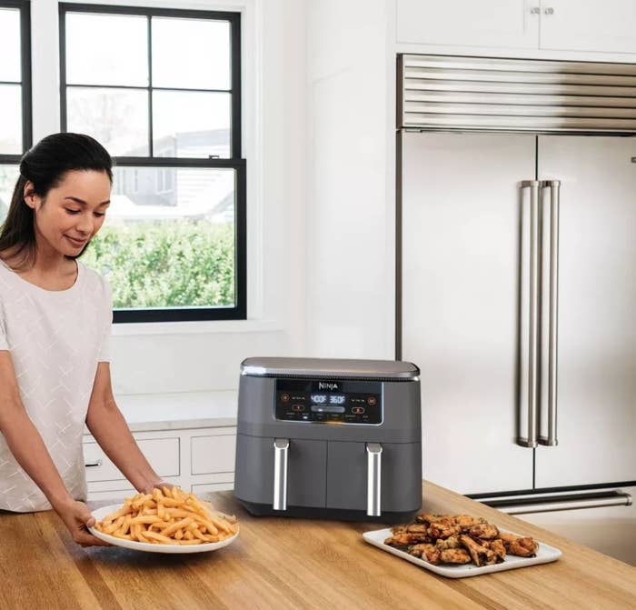 A model serving fries from a dual air fryer