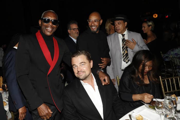 Leo DiCaprio sitting at a table with Swizz Beatz nearby