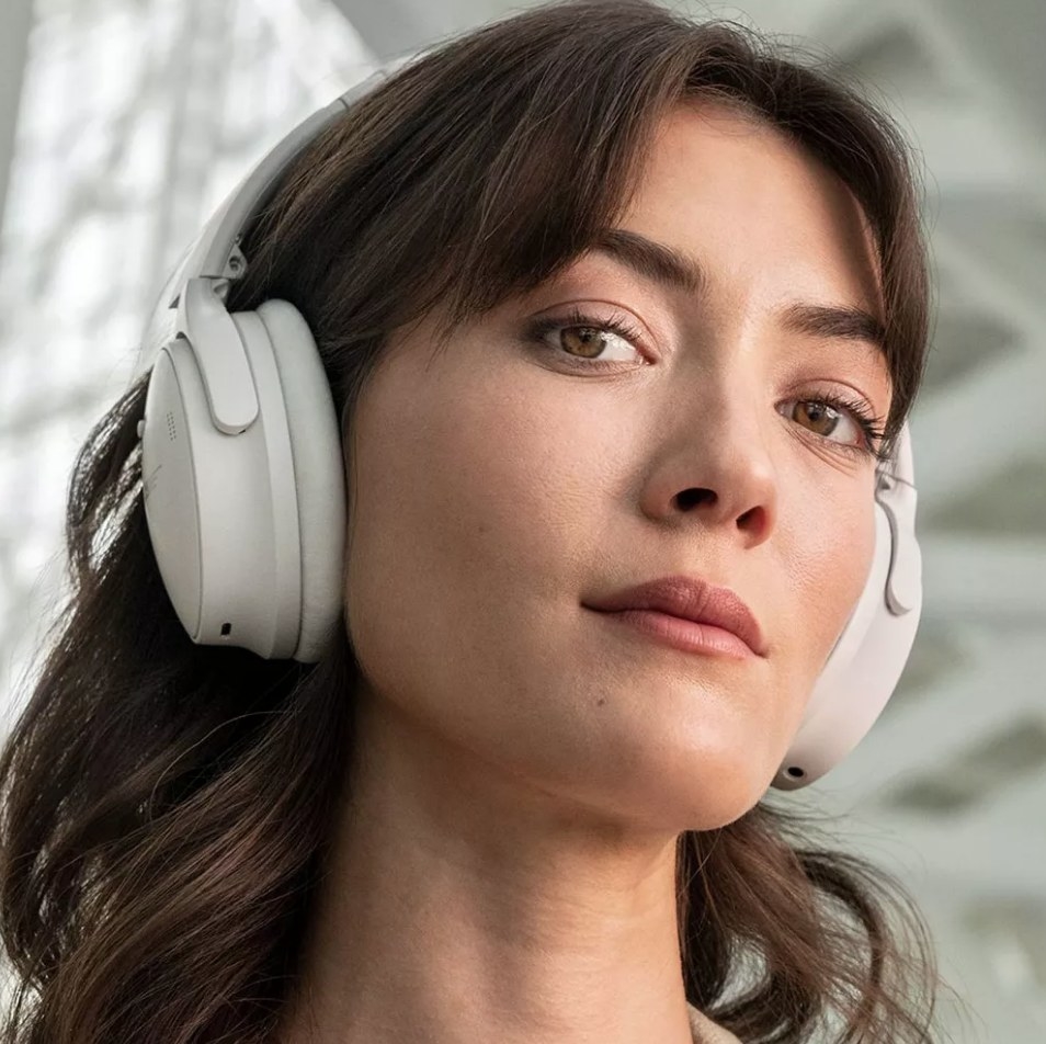 A model wearing white noise-canceling, wireless, bluetooth headphones