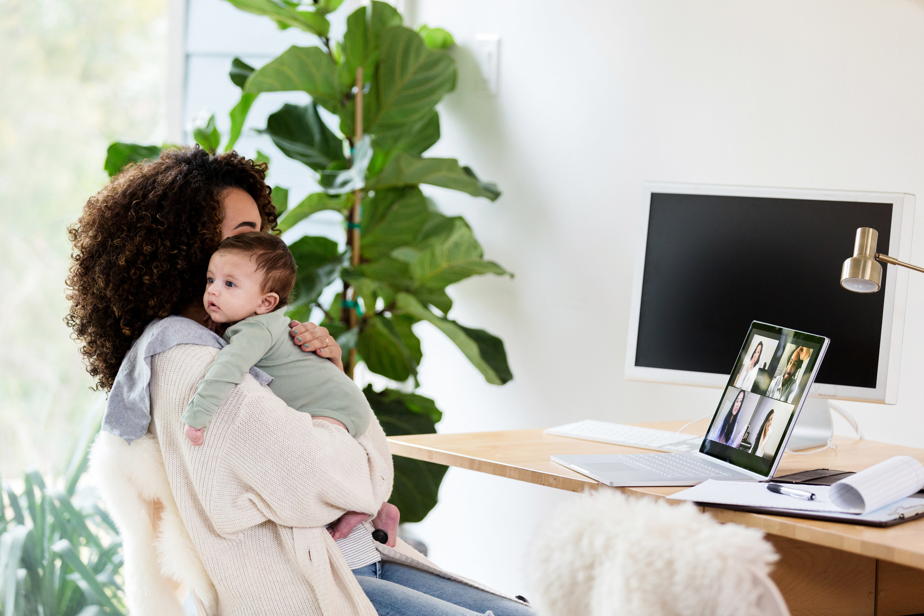 a woman holding her baby in a zoom meeting
