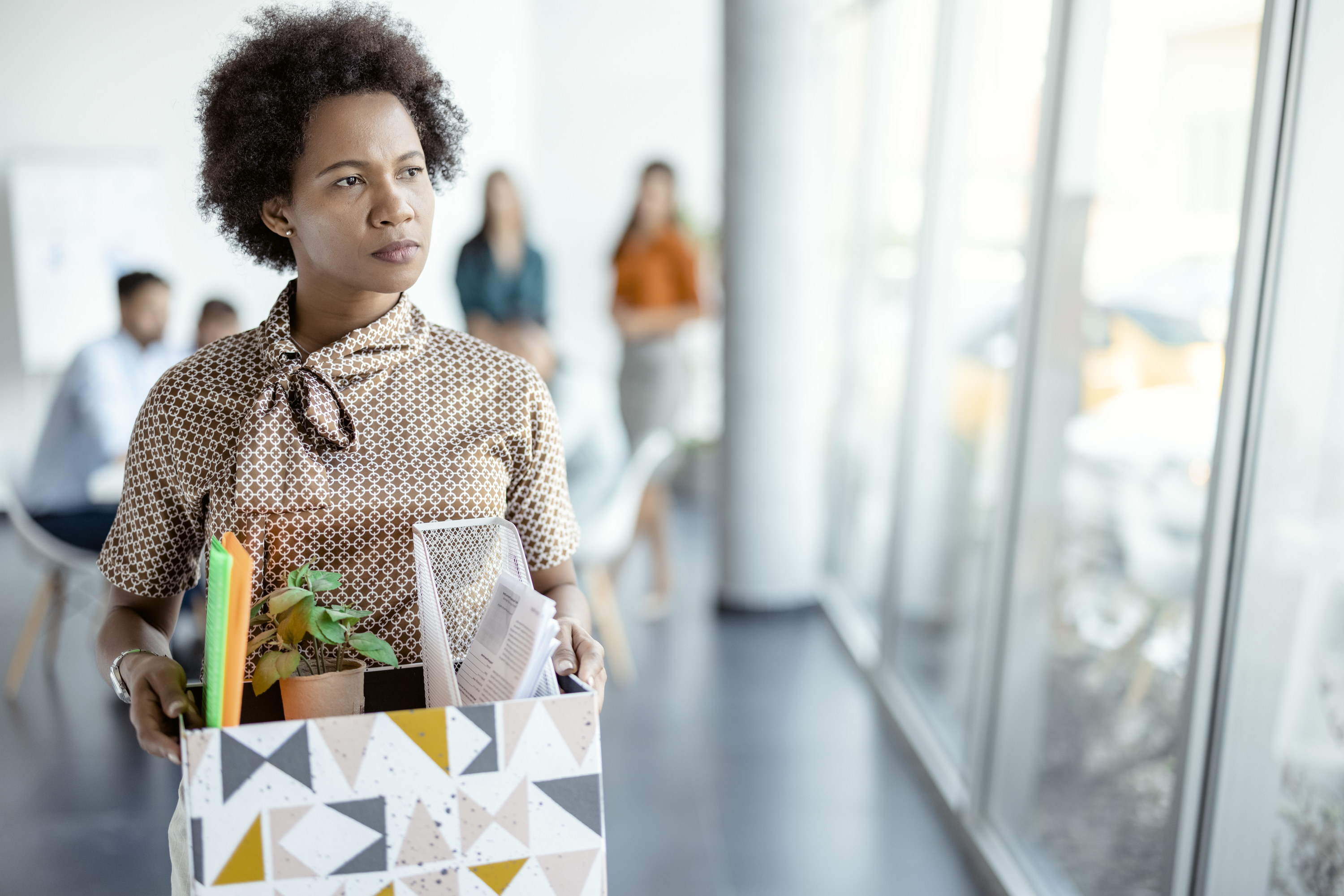 a woman walking out with her things from the office