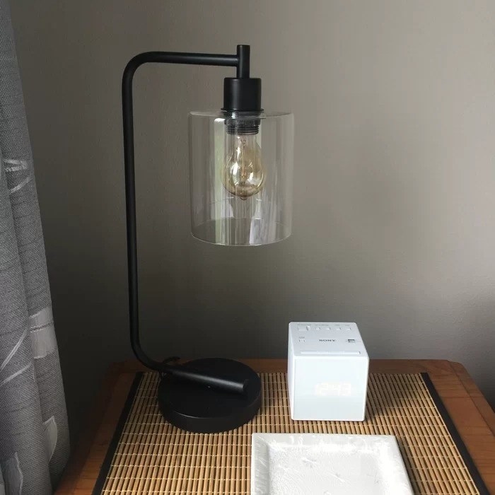 The lamp on a bedside table with an electric alarm clock next to it