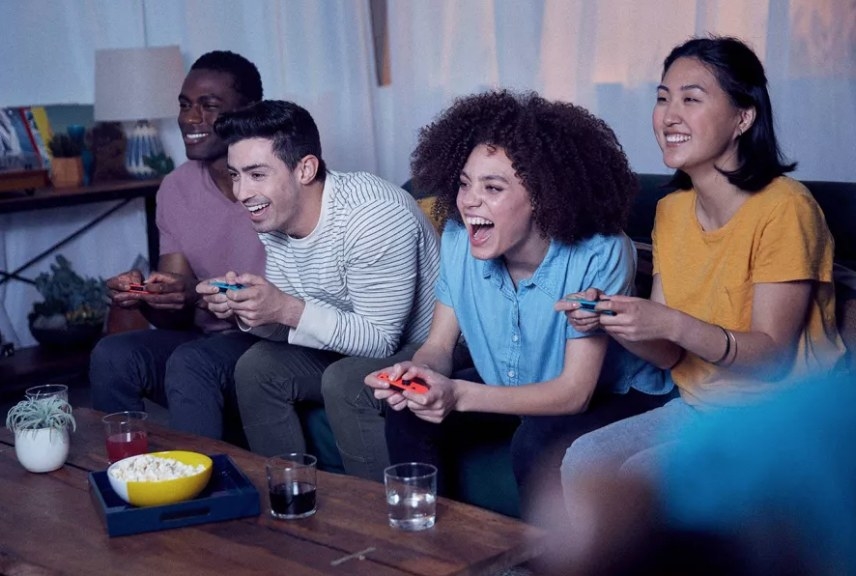 group of friends playing a video game with Nintendo Switch consoles