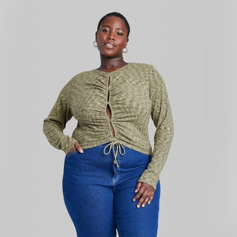 model wearing green lace-up blouse with blue jeans