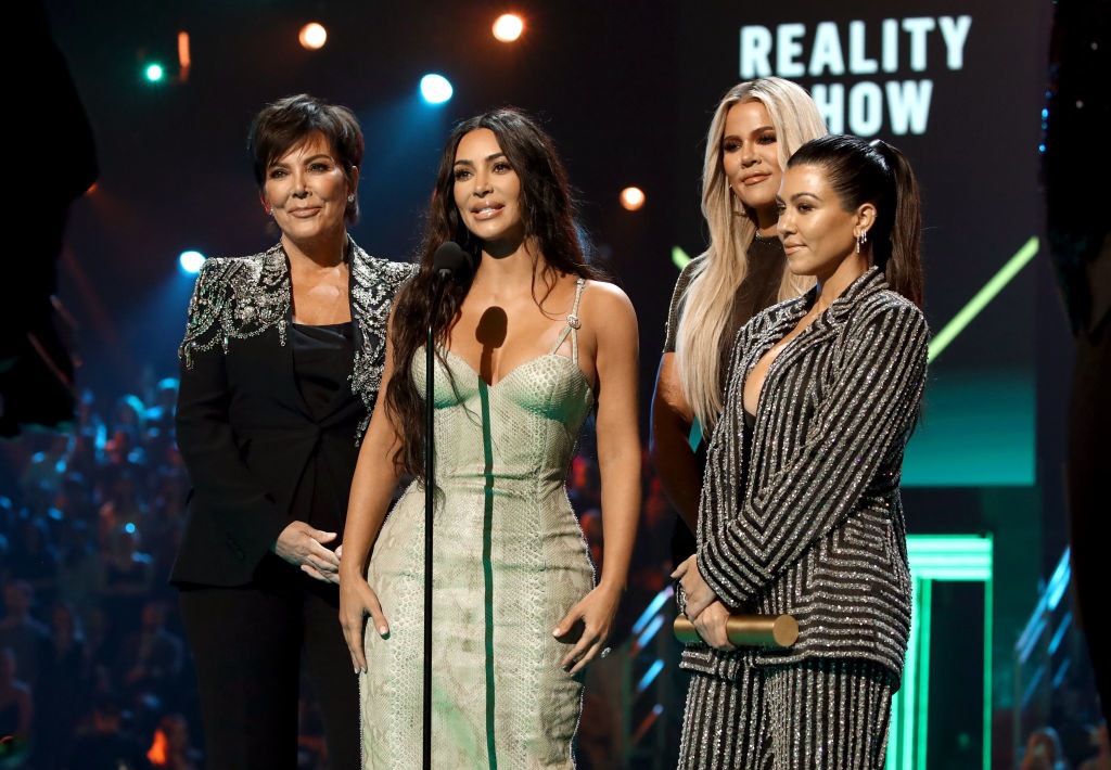 Kris Jenner, Kim, Khloé, and Kourtney stand at a microphone