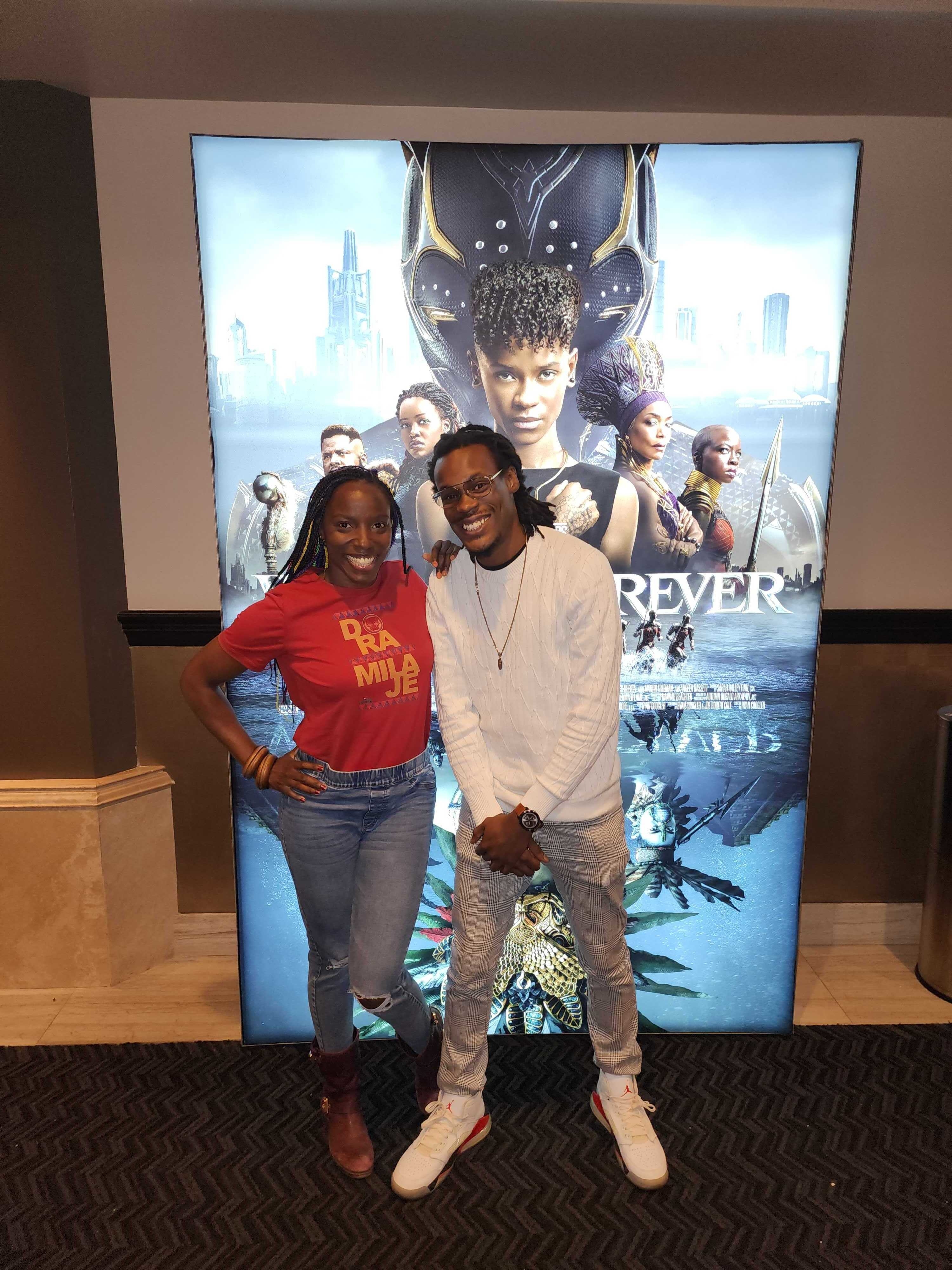 Karlton Jahmal and Janeshia pose in front of a Wakanda Forever Poster