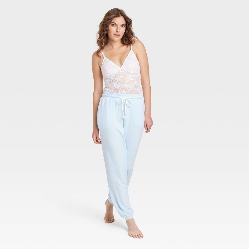 model wearing white lace bodysuit with baby blue sweats