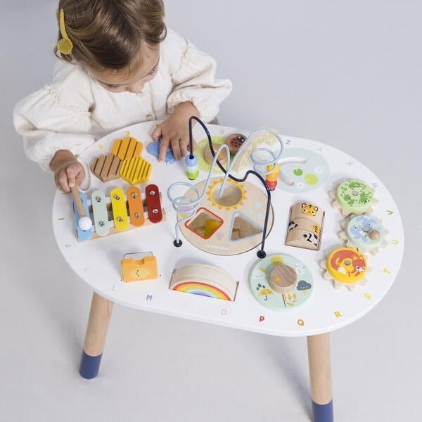 a child model playing at the wooden activity table with various interactive activities mounted on it